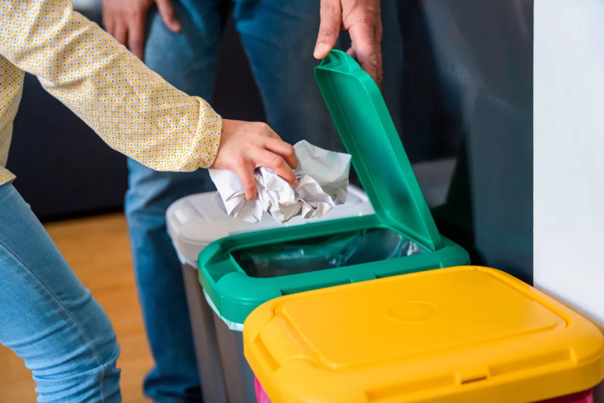 Father and daughter throwing paper into a garbage bin