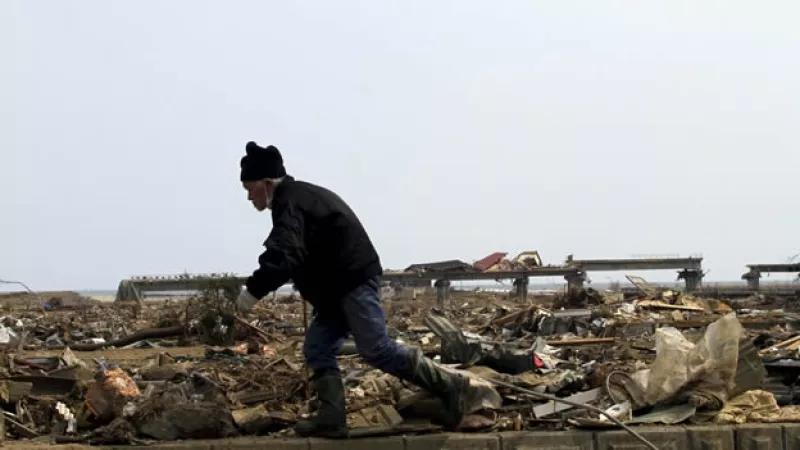 un anciano busca entre los escombros de su casa