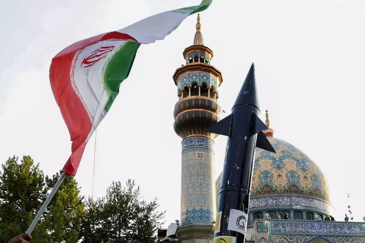 Los iraníes levantan una bandera y la maqueta de un misil durante una celebración tras el ataque de misiles y drones de Irán a Israel, el 15 de abril de 2024, en la plaza de Palestina en el centro de Teherán.