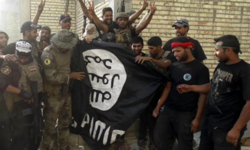 Fuerzas iraquíes sostienen una bAndera de ISIS. (Foto: Reuters)