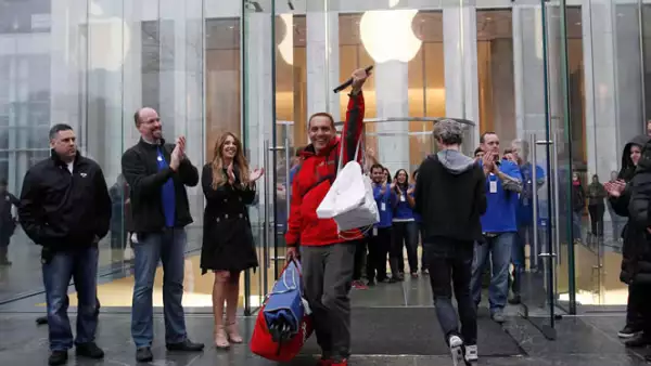 Uno de los primeros compradores sale de una tienda de Apple, entre aplausos de empleados y fanáticos.