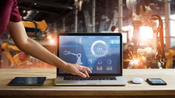 Engineer touching laptop check and control welding robotics automatic arms machine in intelligent factory automotive industrial with monitoring system software. Digital manufacturing operation.Industry 4.