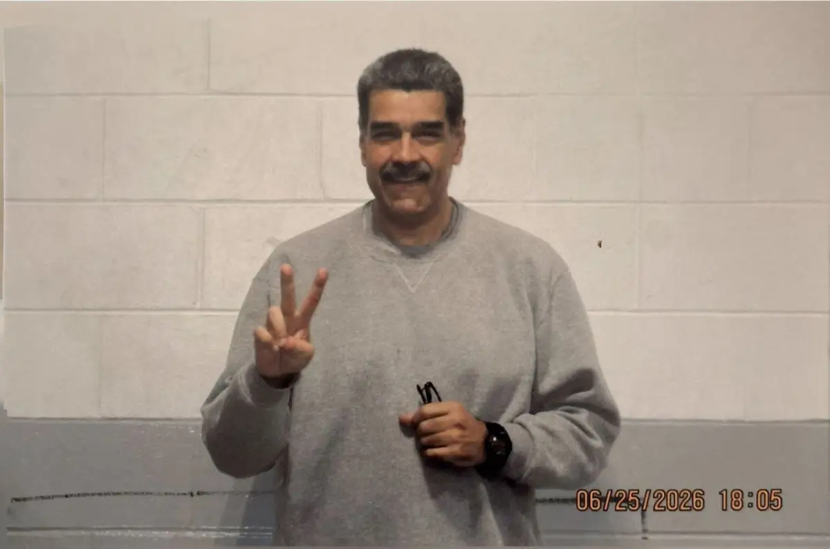 Con un fondo de color gris y blanco, Nicolás Maduro aparece con una sudadera gris, haciendo la señal de paz con una mano, sosteniendo sus lentes y un reloj en su muñeca izquierda.
