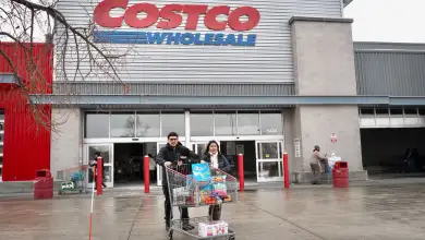 Clientes caminando con un carrito lleno fuera de Costco.