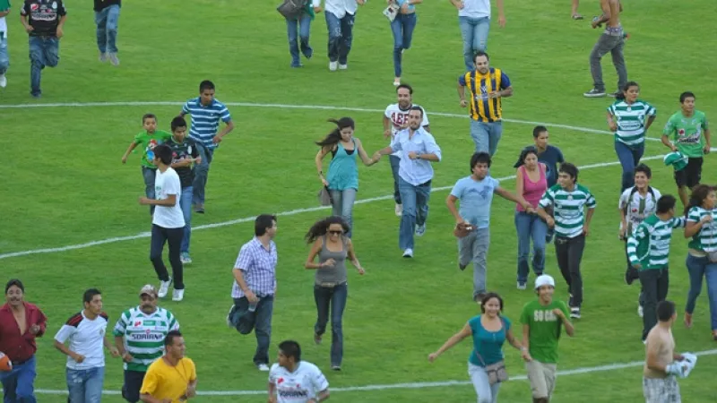 asistentes al estadio corren por la cancha