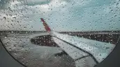 Vista del ala lateral de un avión desde dentro con la ventanilla con poca visibilidad tras el paso de lluvia.