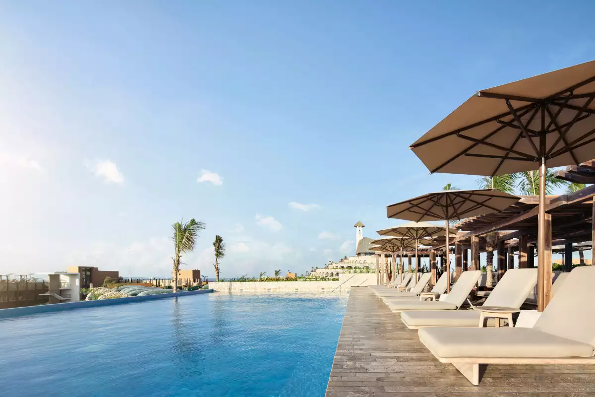Rooftop del Hotel Xcaret Arte con sombrillas y tumbonas frente a la alberca