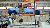Una línea de ensamble de autos chinos en donde se ve como dos trabajadores ensamblar componentes.
