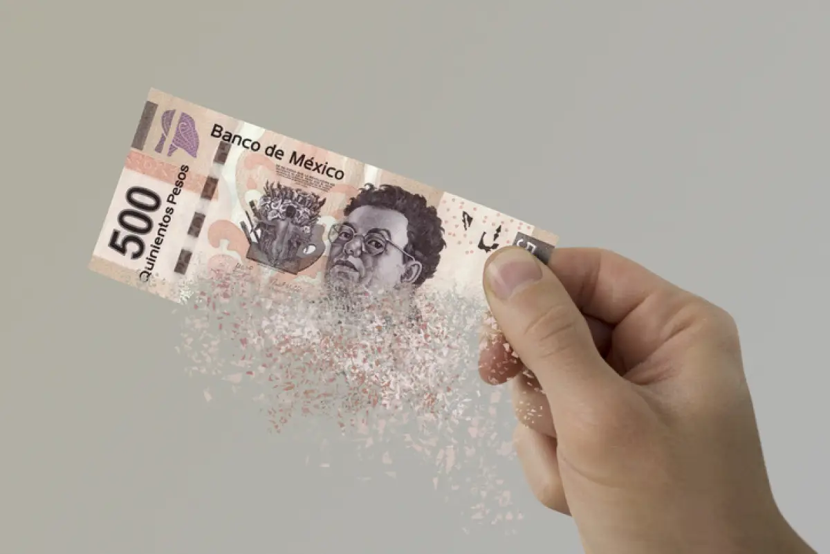 Mexican Pesos bill pulverizes in a man's hand.