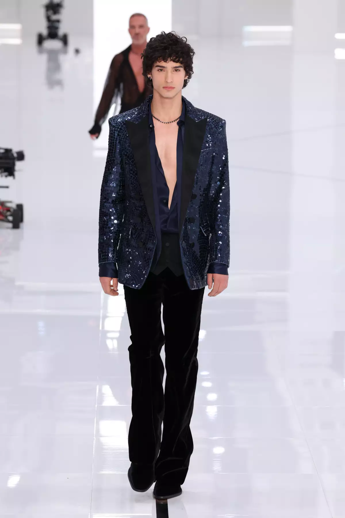 Foto de un modelo en la pasarela de Dsquared2 con pantalones acampanados de terciopelo y un saco brillante.