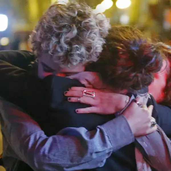 Un grupo de personas se abrazan al salir del teatro en el que más de 100 personas murieron.