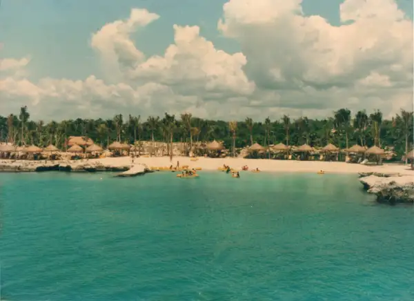 Una foto antigua de los terrenos donde se construiría el emporio de Miguel Quintana Pali. En la foto se observan unos cuantos turistas nadando en una agua cristalina, donde hoy hay múltiples hoteles, restaurantes y toda la cadena de Grupo Xcaret.