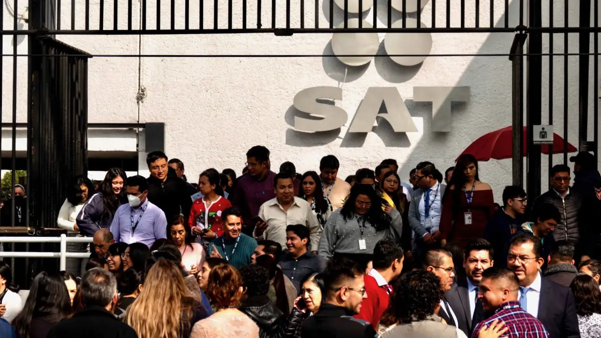 En la imagen se aprecia a trabajadores del SAT haciendo fila para entrar a las oficinas. 