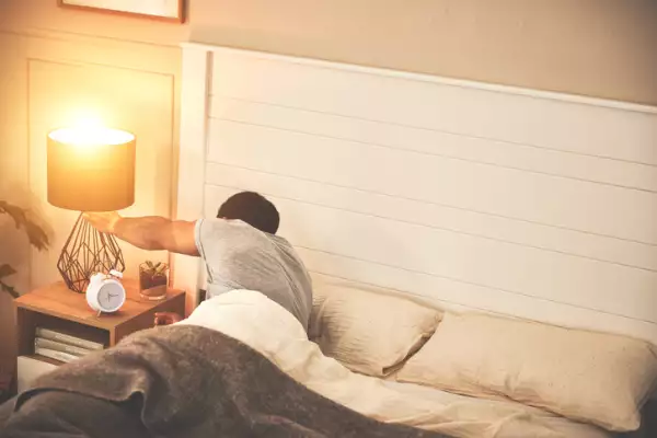 Male switching off bedside lamp.