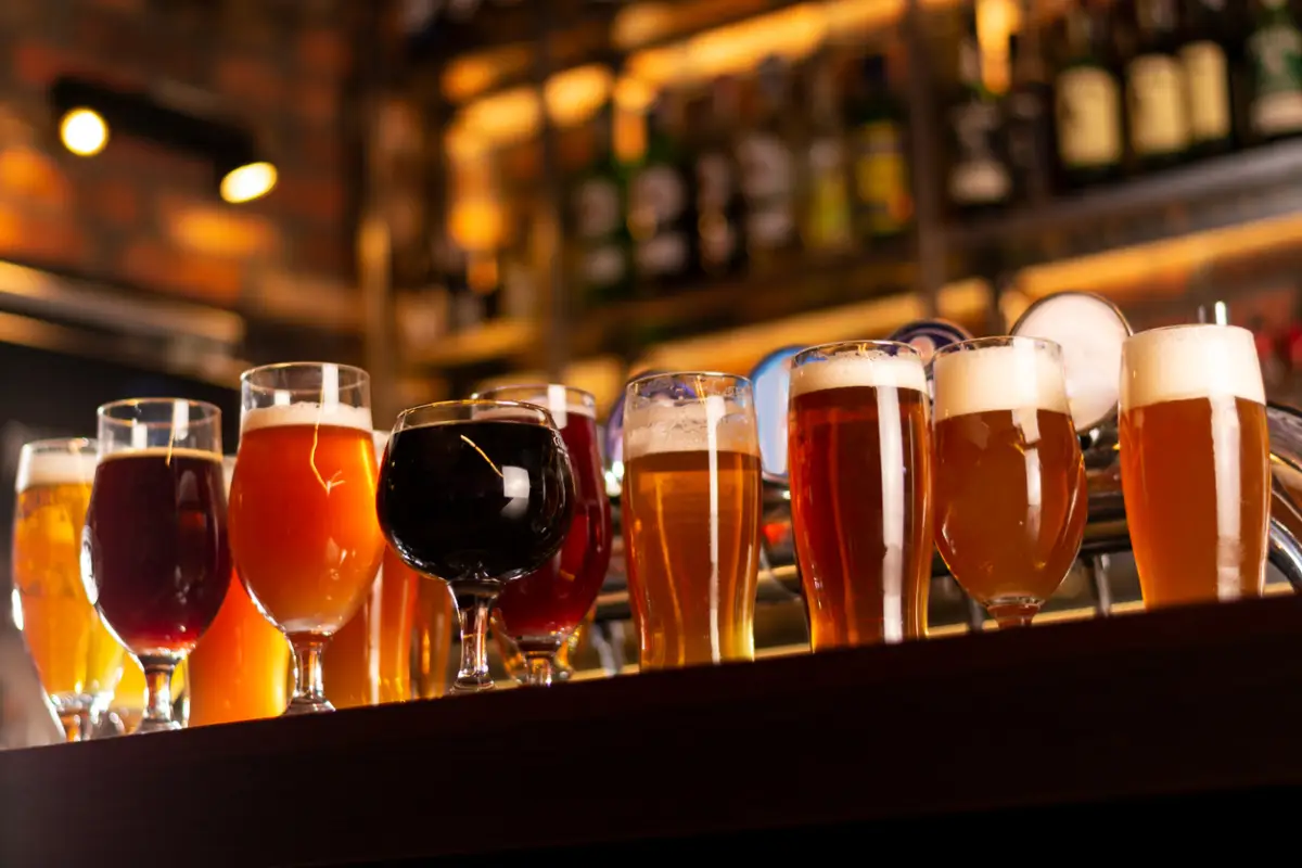 Foto de una mesa llena de vasos llenos condistintos tipos de cerveza