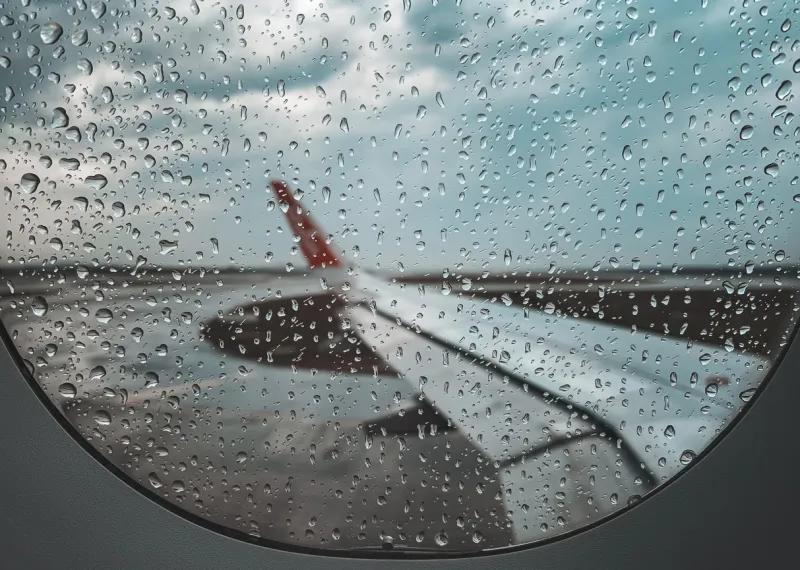 Vista del ala lateral de un avión desde dentro con la ventanilla con poca visibilidad tras el paso de lluvia.
