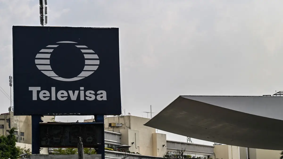 Un cartel con el logo de Televisa en medio de dos edificios. 