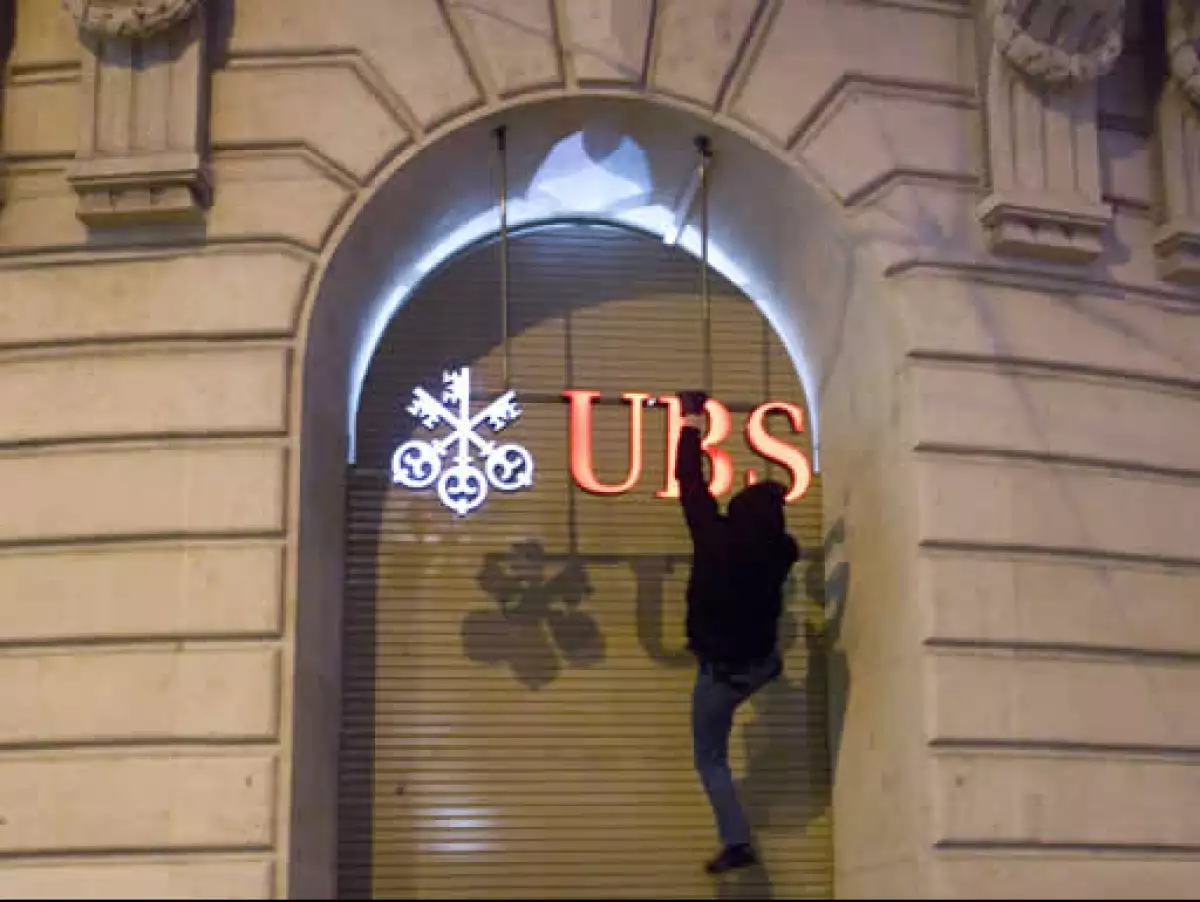 Un activista se colgó del logo de una sucursal del banco suizo UBS en Basilea para protestar contra la cumbre económica que se realiza en Davos. (Foto: Reuters)