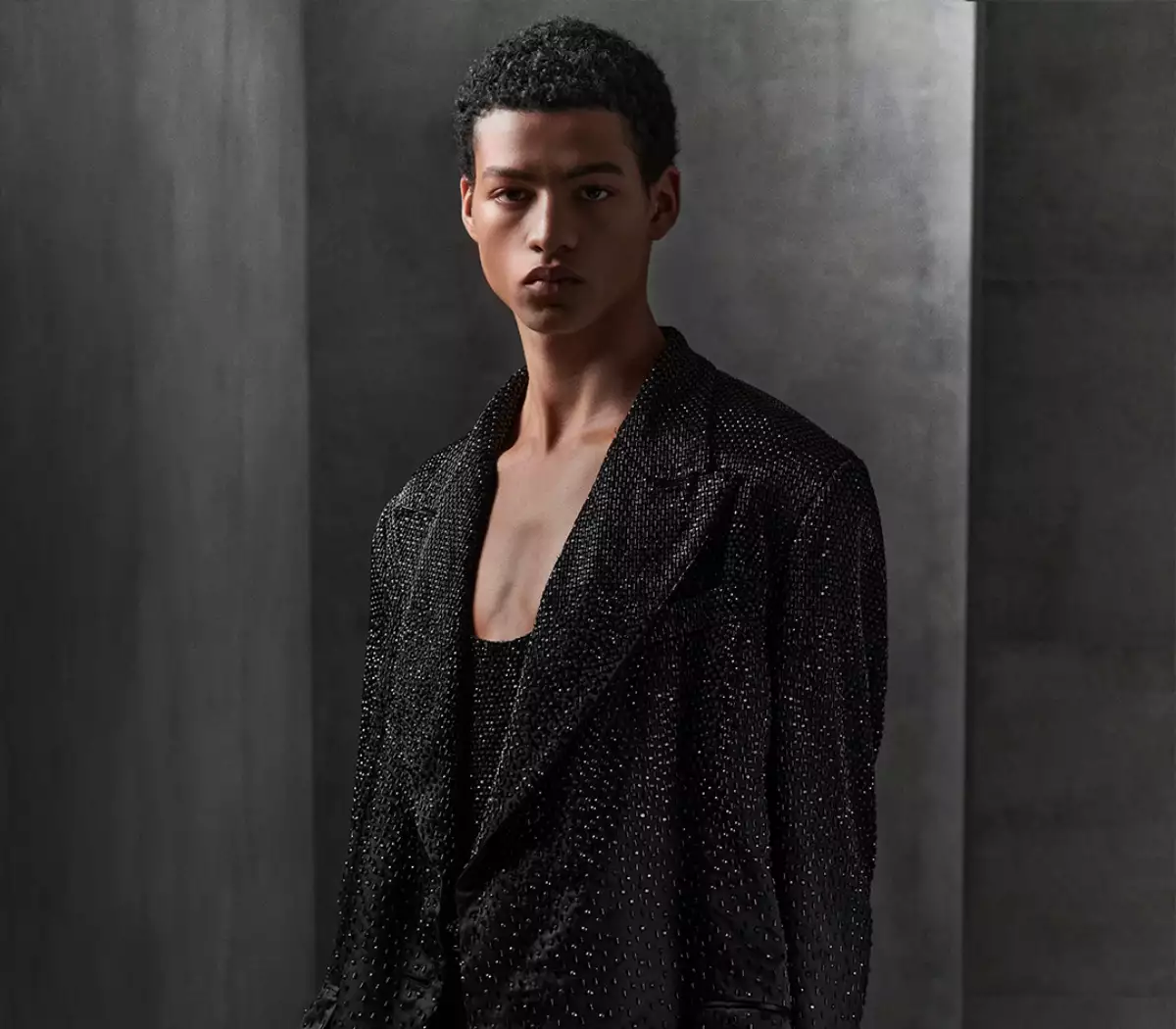 Foto de un modelo de Dolce & Gabbana con un saco negro forrado de lentejuelas negras que dan efecto brillante.