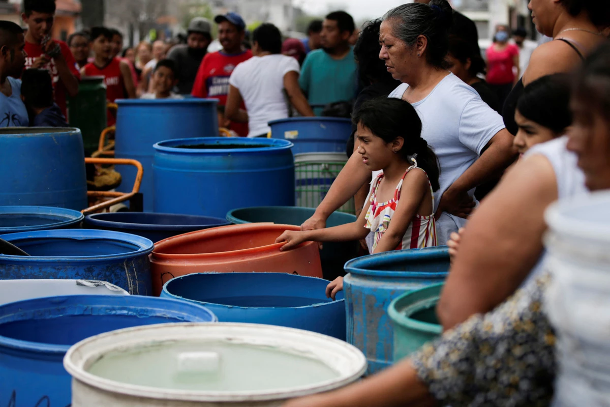 (Decenas de personas cargando contenedores esperan para recibir un poco de agua en Escobedo, Nuevo León)