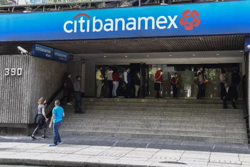 Persona esperan en una fila de una sucursal bancaria.