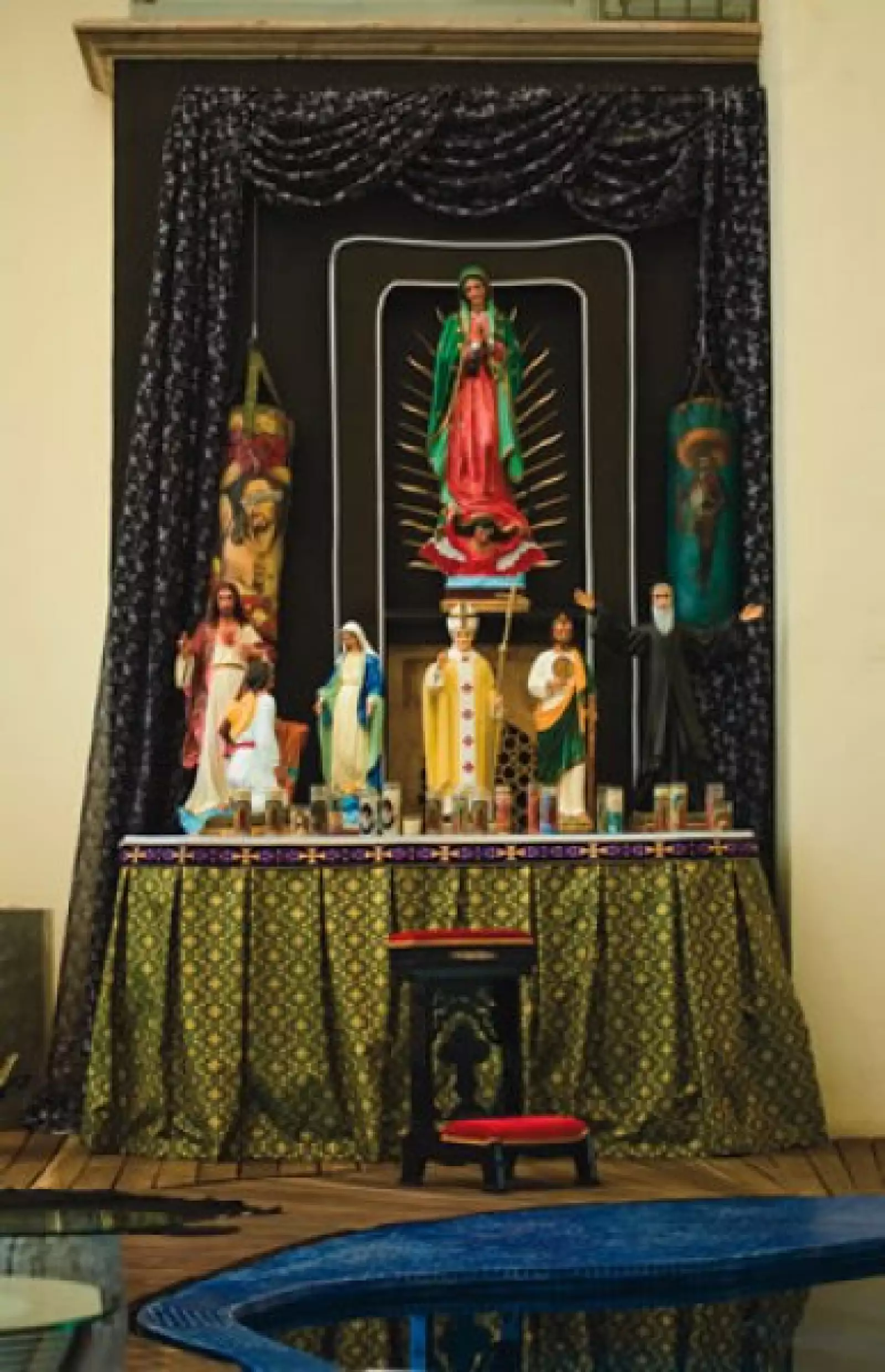 En la alberca hay un altar con una Virgen de Guadalupe y un saco de boxeo con un Cristo, entre otros.