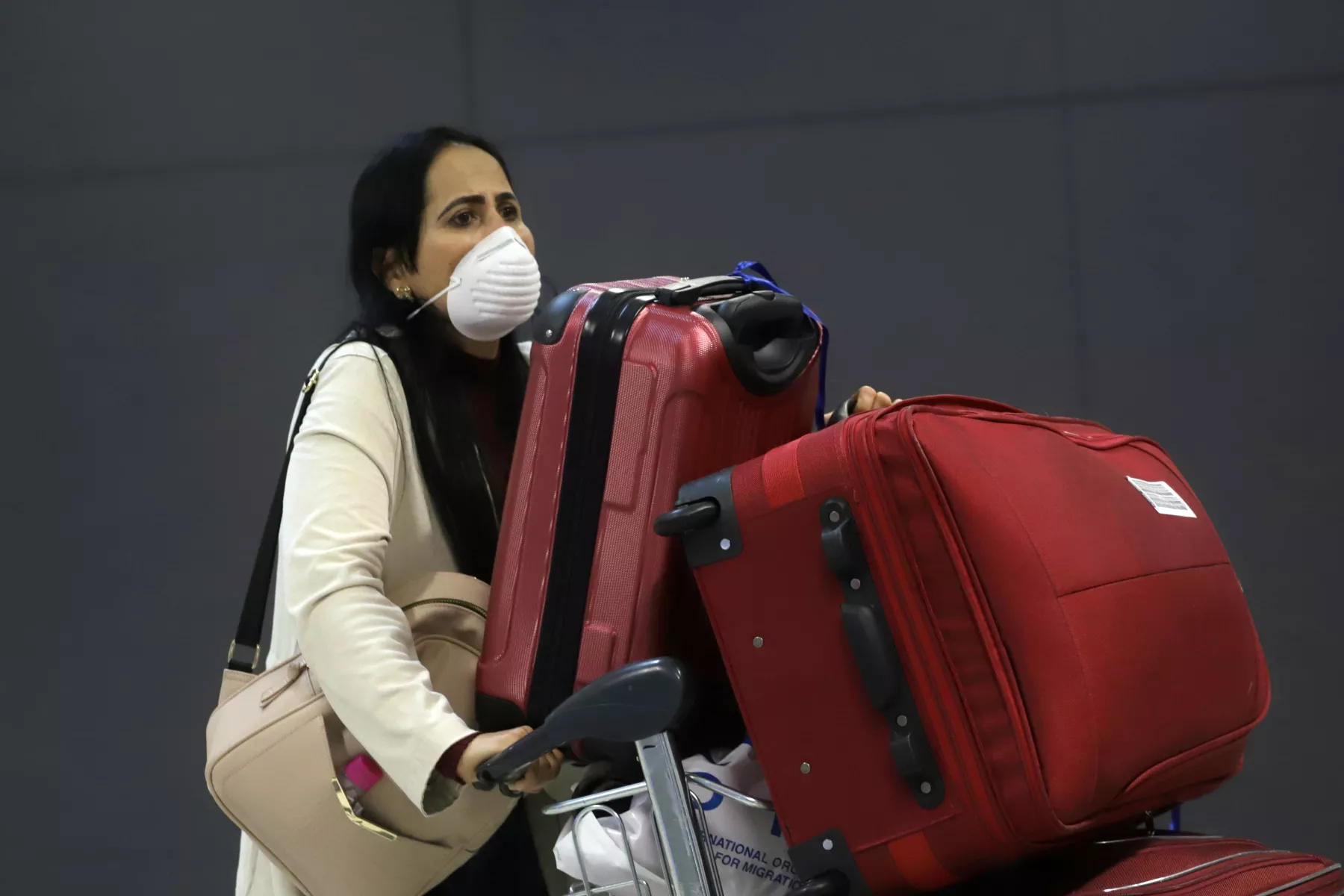A woman wears a protective face mask at international arrivals area at Guarulhos International Airport in Guarulhos