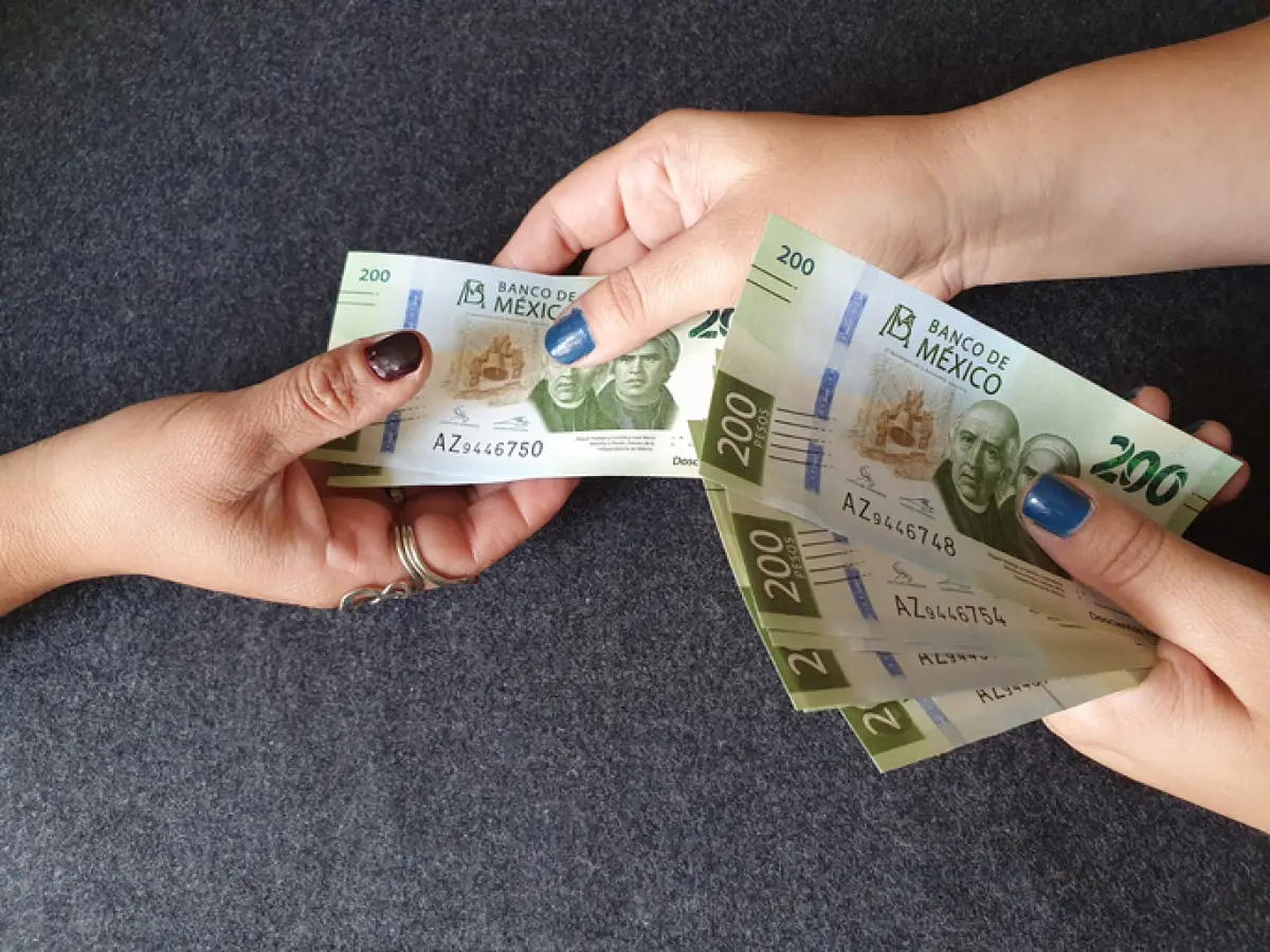Una persona recibe billetes de 200 pesos.