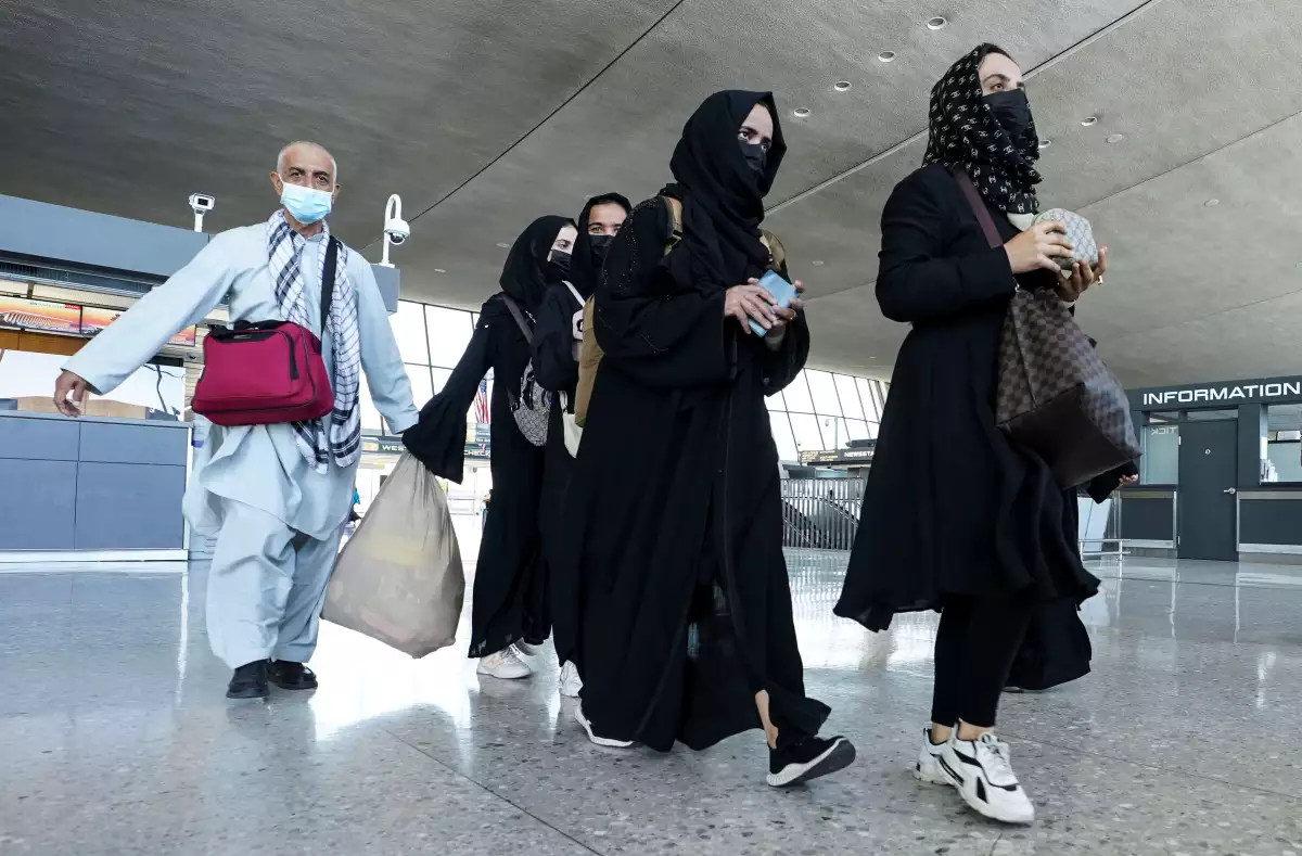 Afghan refugees walk to a bus taking them to a refugee processing center upon arrival at Dulles International Airport in Dulles, Virginia August 25, 2021. REUTERS/Kevin Lamarque