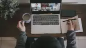 An asian chinese male working at home using laptop video conference call meeting with headset