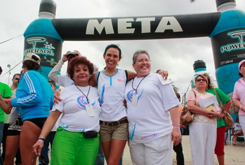 Al centro, Patricia McKelligan acompañada de dos mujeres en la meta del maratón.