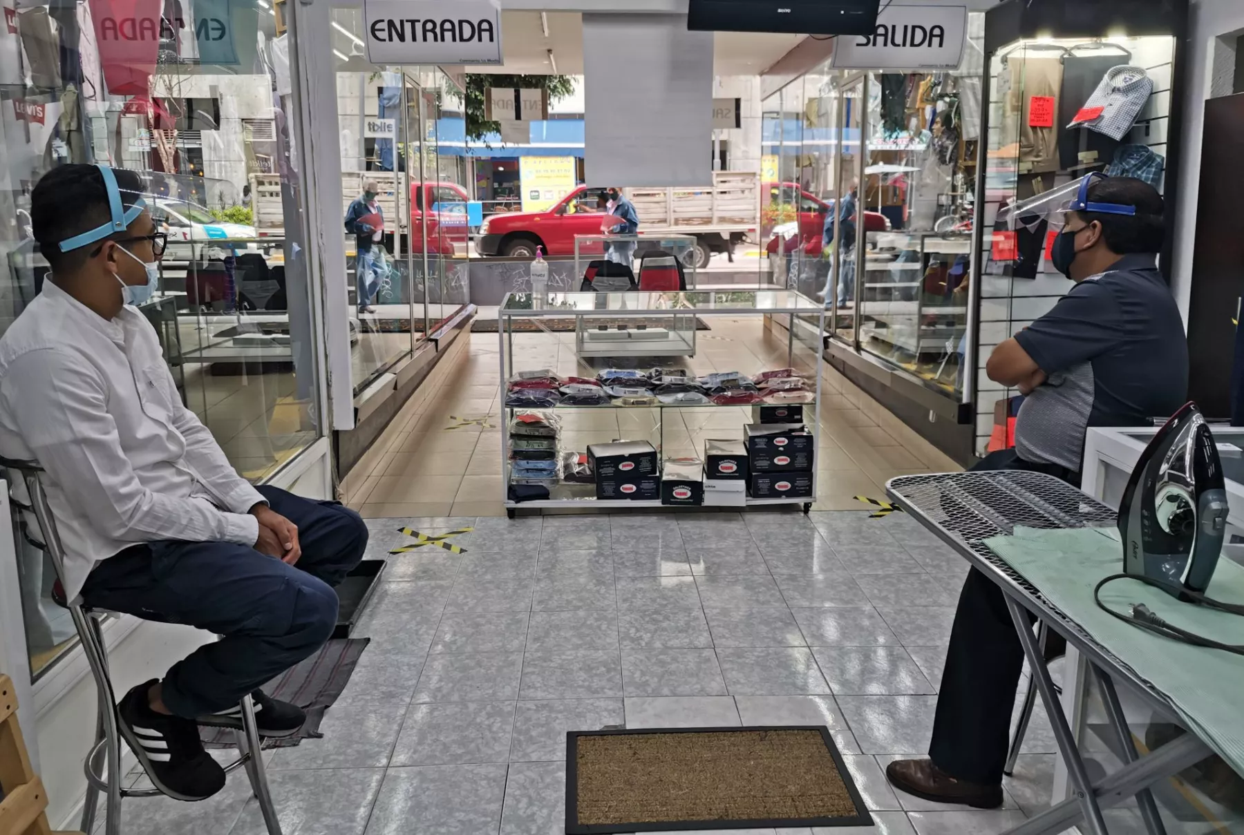 Dos vendedores de una tienda de ropa esperan la primera venta del día, en un comercio del Centro Histórico.