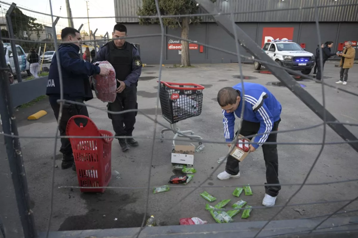 Policías de la provincia de Buenos Aires y un trabajador de un supermercado "Dia" recuperan mercancía en el estacionamiento después de que el supermercado fuera saqueado, en José C. Paz en las afueras de Buenos Aires el 22 de agosto de 2023. Casi treinta personas fueron arrestadas en Argentina después del saqueo de locales comerciales durante el fin de semana en las provincias de Córdoba y Mendoza, eventos que el gobierno describió como "actos criminales" destinados a crear confusión en medio de la campaña para las elecciones presidenciales de octubre. El lunes por la noche se informó de un intento de saquear una tienda en Buenos Aires, que fue impedido por los vecinos.