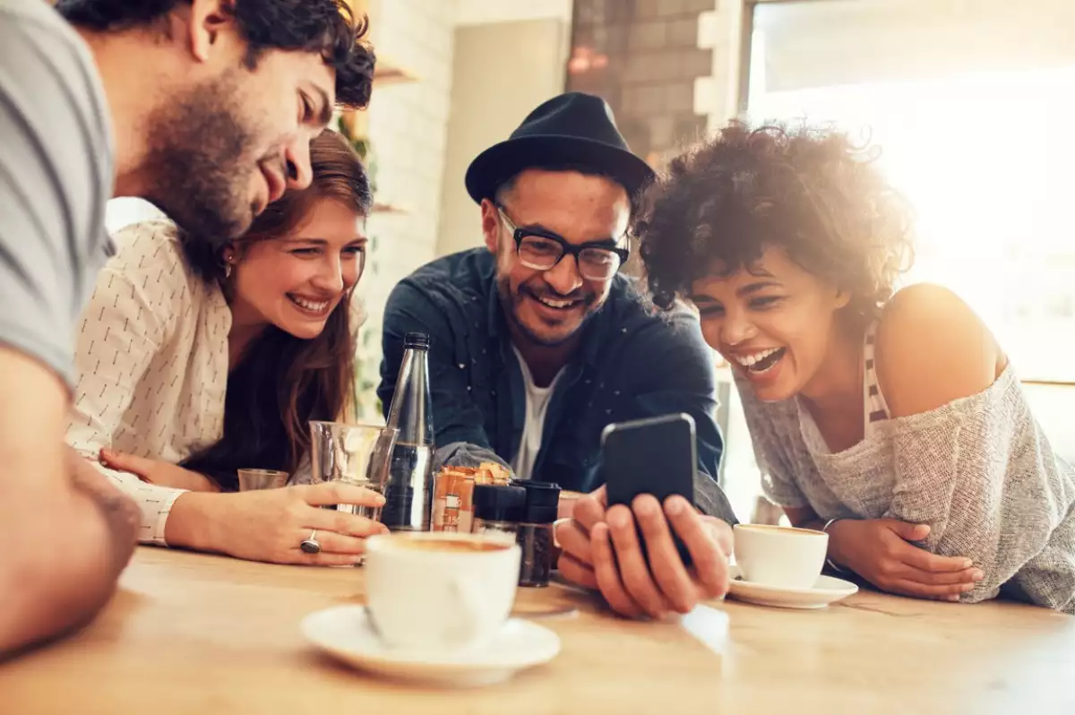 Un grupo de amigos está reunido y comprobando desde un smartphone las novedades de la app de HSBC México, como DIMO y DIAO