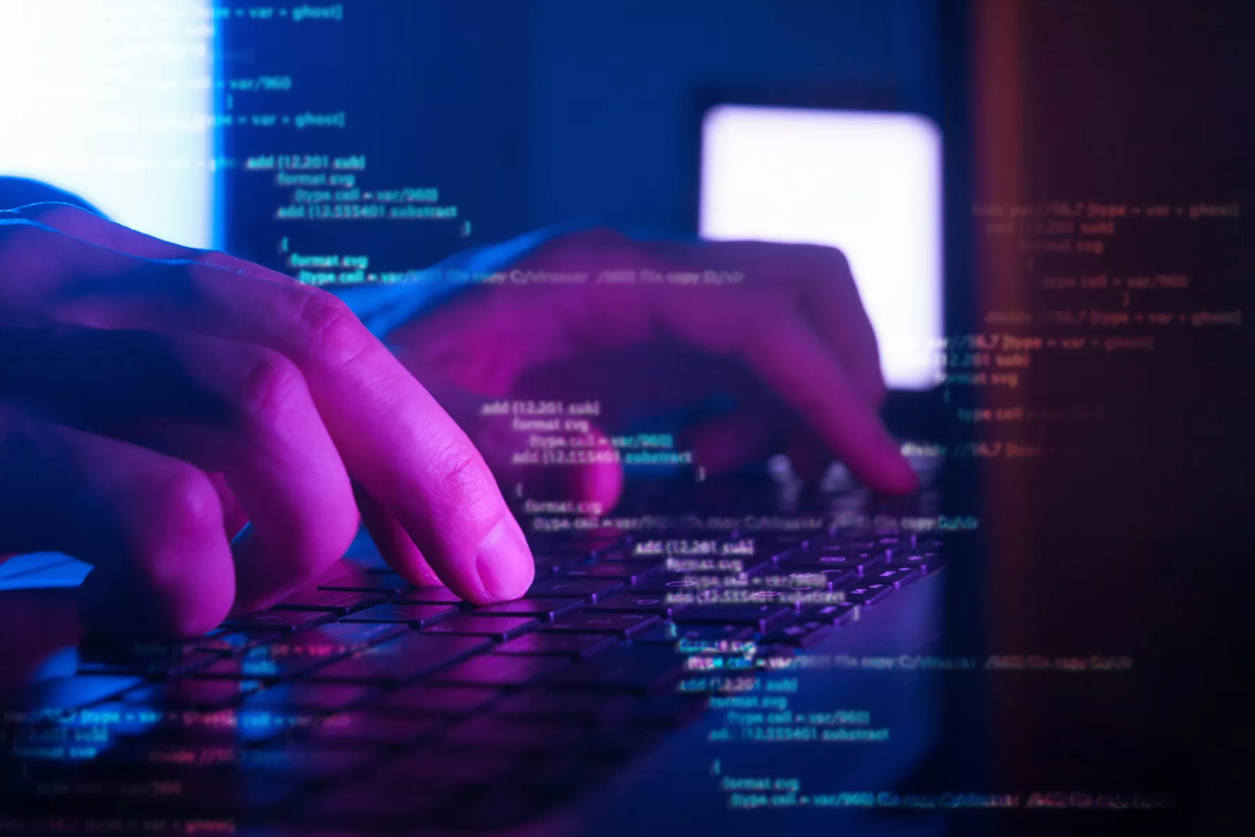 Programador o hacker codificando en una laptop en un cuarto oscuro.