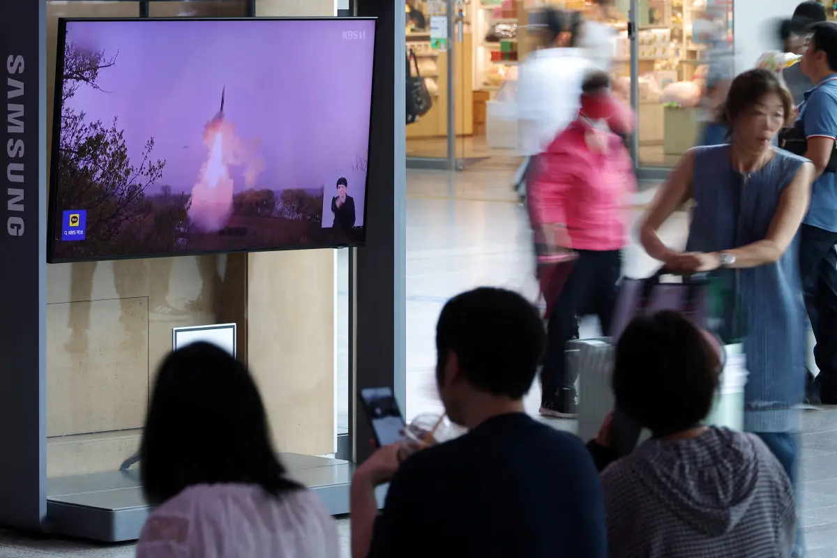 Los pasajeros esperan su tren frente a una televisión que transmite un informe de noticias sobre Corea del Norte disparando un misil balístico frente a su costa este, en una estación de tren en Seúl, Corea del Sur, el 12 de julio de 2023.