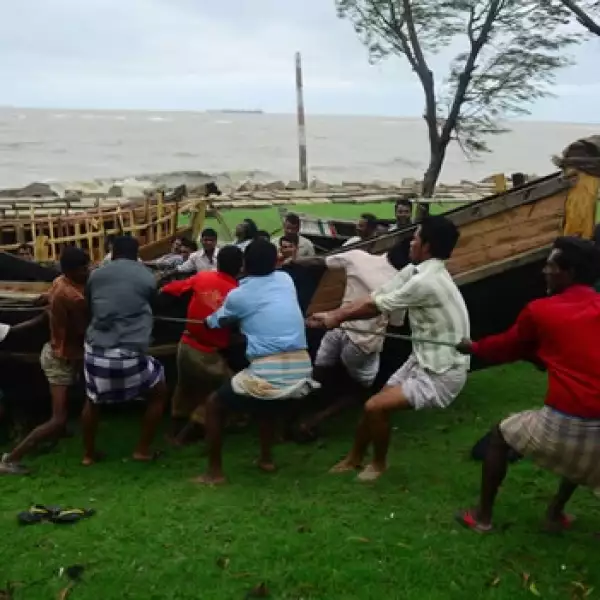 hombres alejan barcas de la playa ante la llegada del huracan Mahasen
