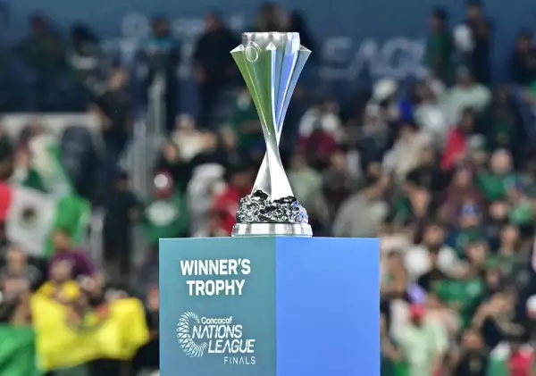 Foto de la copa de la Liga de Naciones de la Concacaf sobre un pedestal y detrás se ven aficionados de México.
