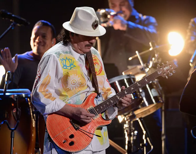 Foto de Carlos Santana en un escenario tocando la guitarra