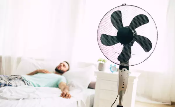 Man trying to refresh from the heat with a fan.