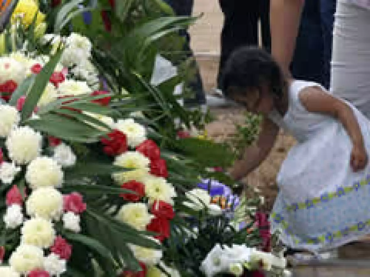 Ua pequeña deposita una flor durante el entierro de las víctimas del incendio. (Foto: Reuters)