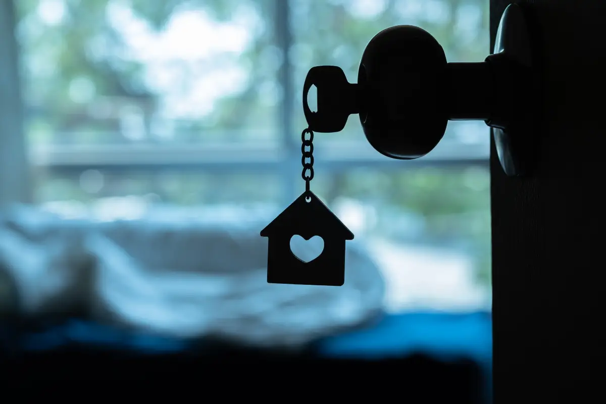 House key with home keyring in keyhole on wood door, copy space