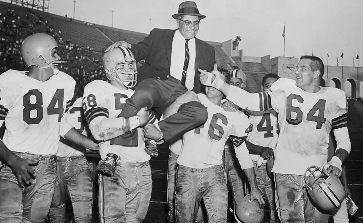 Foto de Vince Lombardi vestido de traje y sombrero cargado en hombros de los jugadores de los Packers tras vencer a los Rams.