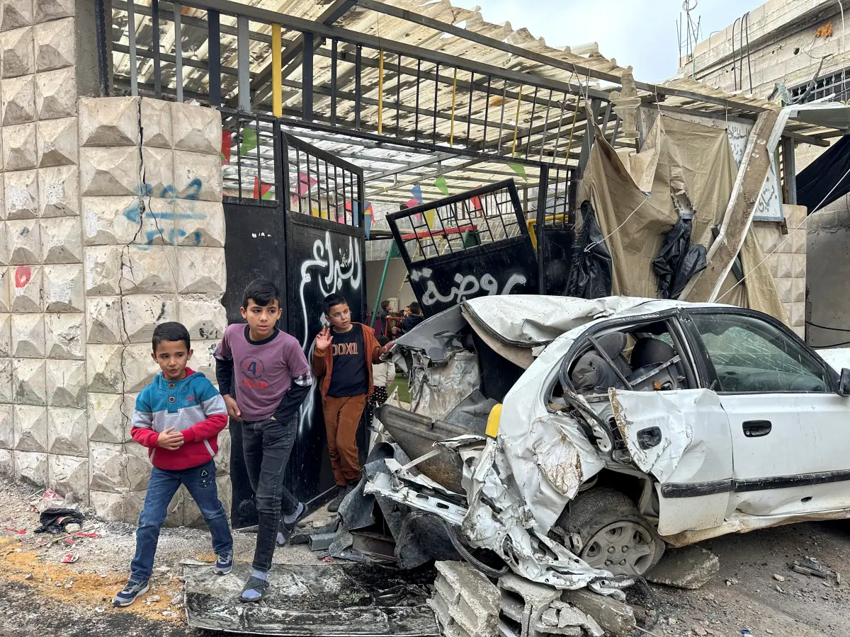 Los niños palestinos caminan cerca de un coche dañado después de una incursión israelí, en Tulkarm, en la Cisjordania ocupada por Israel, el 17 de diciembre de 2023.