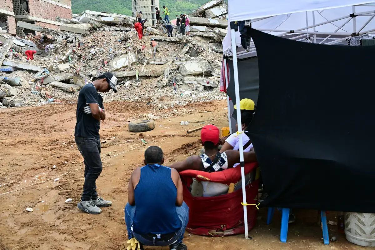 La gente espera noticias sobre los cuerpos de sus seres queridos frente a un edificio derrumbado en Caraballeda, estado de La Guaira, Venezuela, el 12 de julio de 2026, después de los terremotos gemelos que azotaron la región.