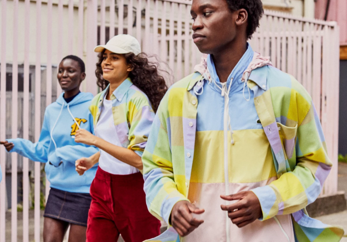 Tres modelos, dos mujeres y un hombre vestidos con prendas coloridas de Lacoste.