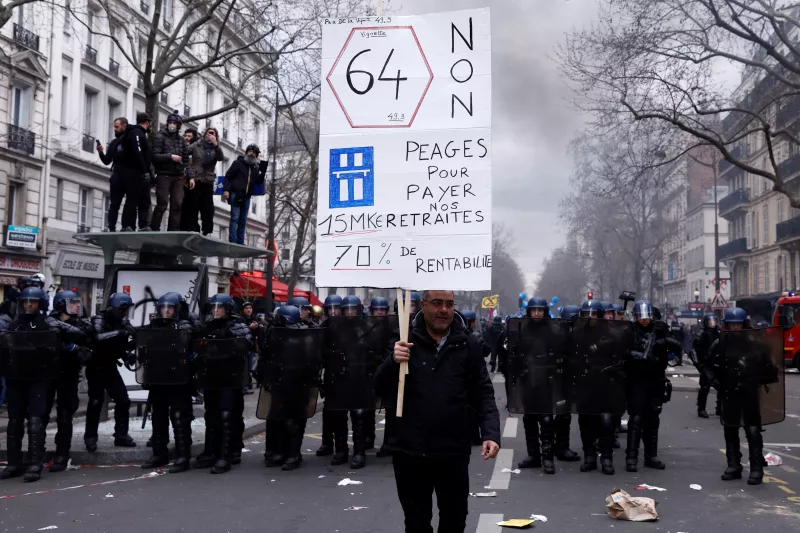 Un manifestante sostiene un cartel frente a los gendarmes franceses en posición durante una manifestación como parte del décimo día de huelgas y protestas nacionales contra la reforma de las pensiones del gobierno francés, en París, Francia, el 28 de marzo de 2023.