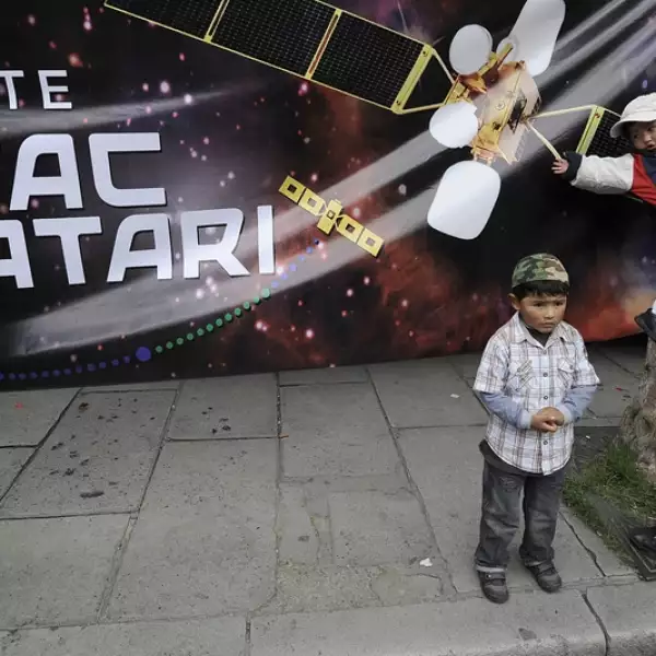 personas junto a un letrero del satelite tipac katari