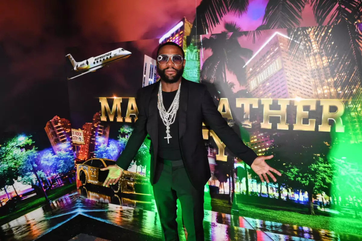 Floyd Mayweather vestido de blazer, playera y pantalón negros con collares de oro blanco.