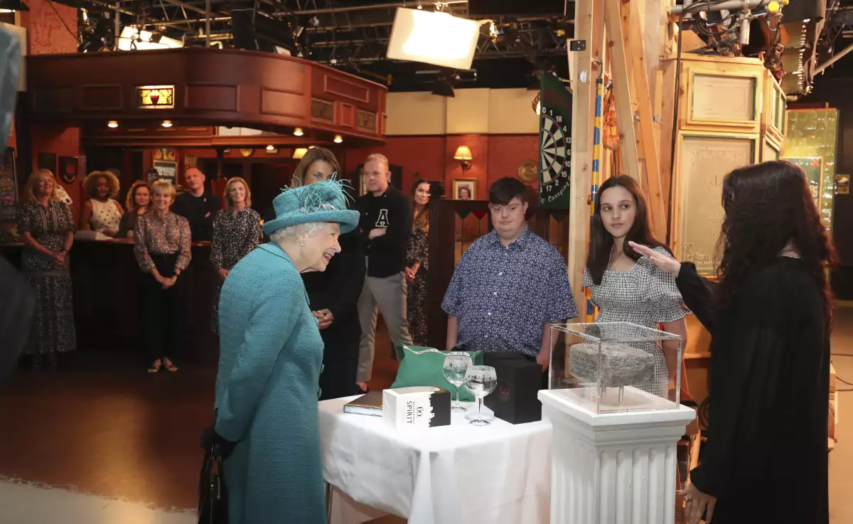 La reina Isabel recibiendo algunos de los regalos que la producción de "Coronation Street" preparó para ella.